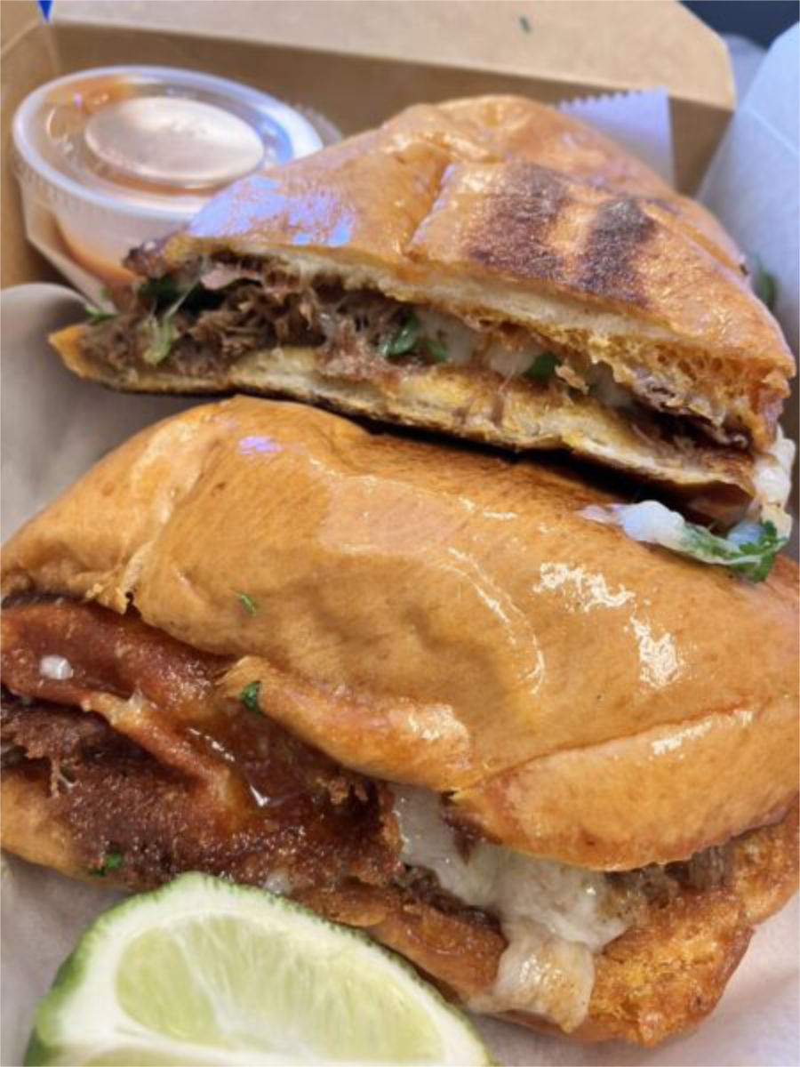 Fresh Mexican torta stuffed with tender birria, beans, and vegetables